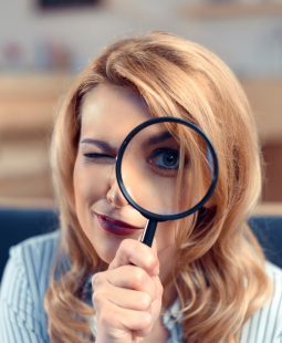 attractive young businesswoman looking through magnifying glass
