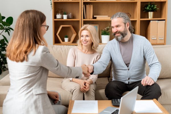 Happy mature bearded man giving hand to young real estate advisor